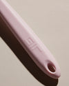 Close up of the Light Pink Flip handle on a cream background. 