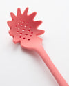 Close up of the Ultimate Spaghetti Spoon in Red on a cream background. 
